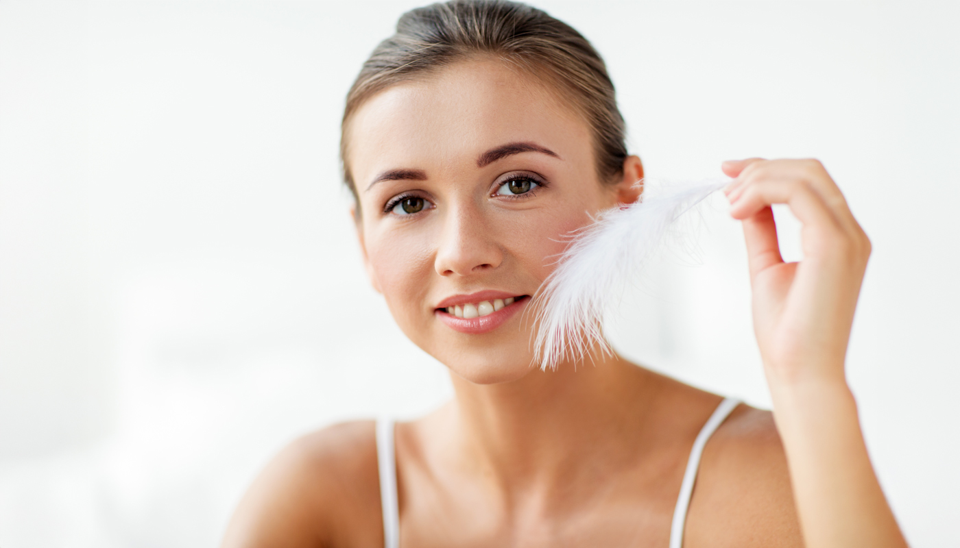 Primo piano di ragazza con piuma accostata al viso